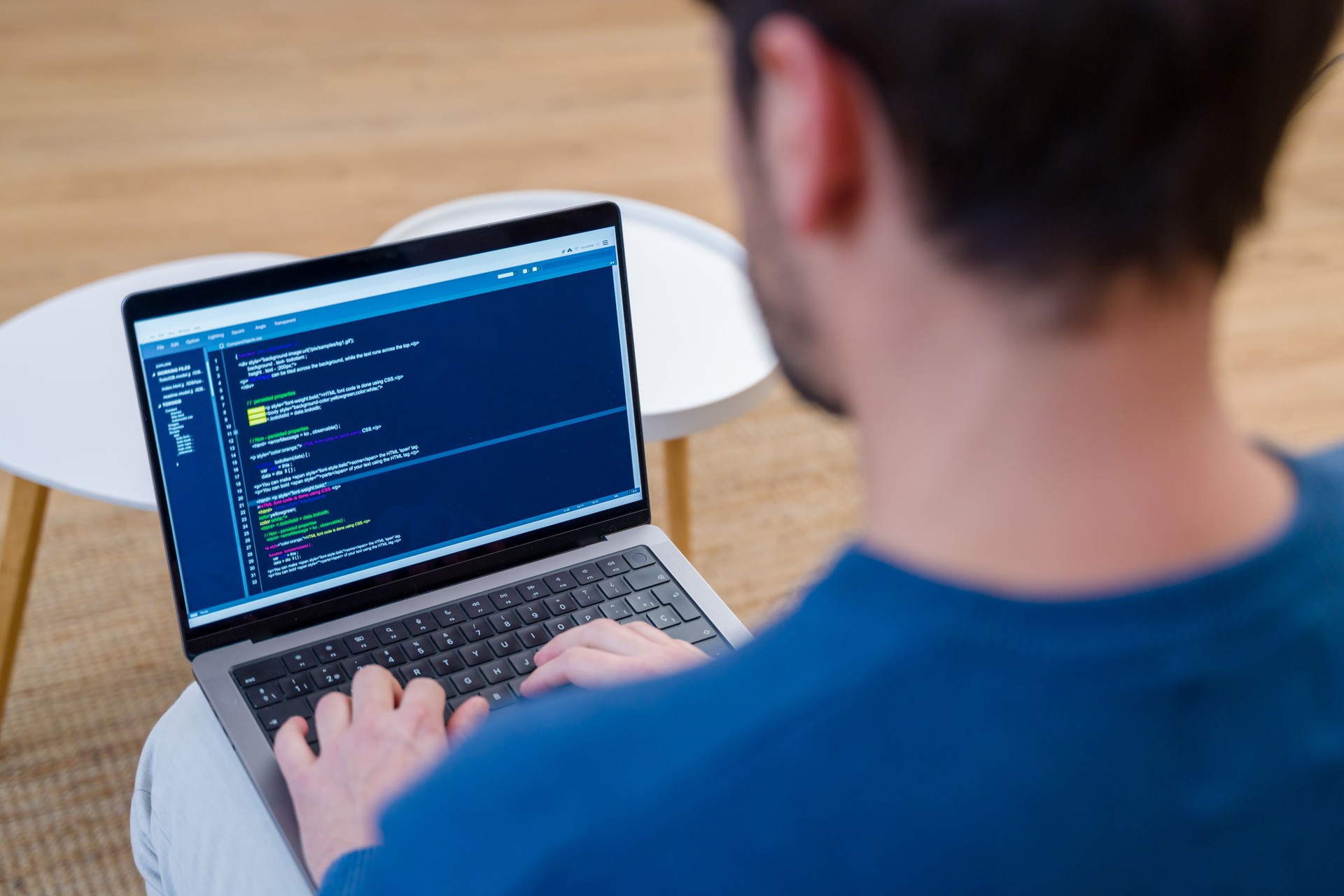 Computer programmer writing code on a laptop, working from home